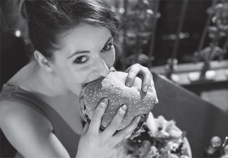 Frau isst Burger mit den Händen